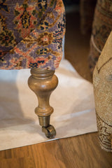 Turned wooden leg, brass caster, and purple Bibikabad Persian rug fragment pile.