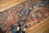 Antique Persian Serapi rug's blue and coral geometric pattern, wear, and frayed edges.
