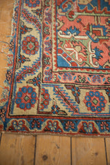 Fragmented corner of antique Serapi runner, tattered edge, blue and red floral patterns on beige.