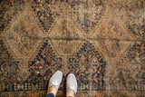Decorative distressed pile on a vintage Shiraz rug with blush, navy, and coffee tones.