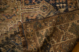 Distressed brown and navy pile of a vintage Shiraz rug, showing its hand knotted geometric foundation.