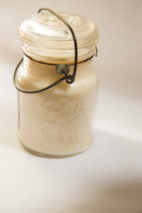 Vintage Ball IDEAL glass jar candle, showcasing embossed text, rusted wire bail, and creamy wax.