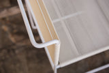 White tubular armrest and textured beige spaghetti cording on the vintage chair.
