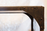 Detail of the antique industrial table's riveted cast iron frame and soapstone edge.