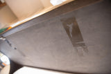 Underside of antique soapstone table with visible tape, velcro, and use marks.