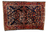 Distressed vintage Bibikabad rug with floral bouquets on a navy field framed by a black cherry border.