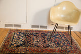 Distressed vintage Bibikabad rug with indigo and cherry floral motifs styled in a modern room.