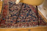 Styled view of a distressed vintage Bibikabad rug with rich indigo and cherry tones.