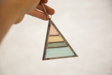 Hand holds Stained Glass Art with pink, yellow, green, and blue opaque panels.