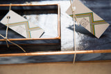 Debbie Bean branding tags on copper-patinaed stained glass tray, showing marbled blue-black base.