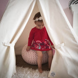 Natural canvas teepee interior showing a child sitting on a pink pouf.
