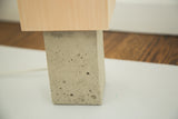 Visible pockmarks on the light grey concrete base below natural maple wood.