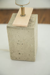 Textured gray concrete base and light maple veneer detail of the table lamp.