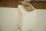 Hand-poured white plaster base and walnut wood veneer detail of modern lamp.