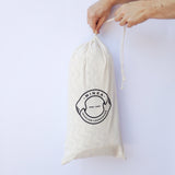 Hands closing natural canvas drawstring bag with Minka Inhouse handmade logo.