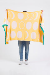Yellow blanket showcasing pink moon phase pattern and bright green knit border.