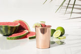 Pure copper cup with a bright, reflective finish, garnished with lime and watermelon.
