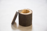 Handmade wooden ring box from salvaged log, featuring natural bark texture and a ring.