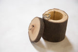 Handmade wooden box, partially open, with a ring on its rustic bark-textured rim.
