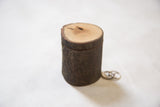 Natural bark textured wood ring box with light wood lid, shown next to wedding rings.