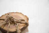 Natural wooden coaster's live edge and visible wood grain tied with rustic twine.