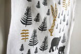 Screen-printed black fern, golden rabbit, and bear motifs on natural linen.