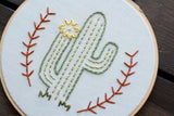 Handmade green cactus embroidery with yellow flower and orange branch stitching.