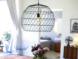 Black wire sculptural Array Pendant light with a warm glowing bulb.