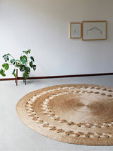 Textured natural hemp round rug featuring intricate concentric and scalloped patterns.