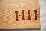 Four dark butterfly inlays mending a natural crack in light hickory wood.