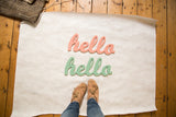 Hand-cut, distressed wooden 'hello' signs in seafoam green and soft peach.