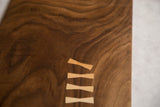 Rich walnut wood serving board featuring five light wood butterfly joinery inlays.