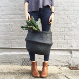 Charcoal Olli Ella belly basket, handwoven seagrass with two-tone texture, full of greens.