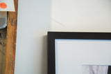 Detail of the black wooden frame and white mat around the photograph.