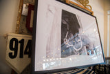 Angled close-up of the black-framed horse photograph, reflections, and striped textile.