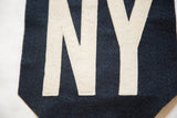 Cream felt letters N and Y with visible hand-sewn stitching on navy felt.