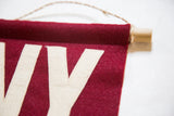 Detail of crimson felt flag with hand-sewn cream letter Y and oak dowel.