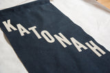 Cream felt KATONAH letters hand-sewn diagonally on a navy felt banner.