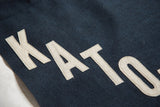 Cream felt letters KATO hand-sewn on a navy banner, diagonally positioned.