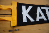 Close-up of black felt pennant texture with white Katonah letters and yellow trim.