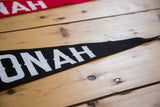 Black felt pennant with white 'ONAH' letters against wooden planks.