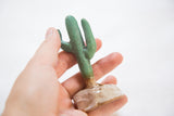 Handmade ceramic cactus held in hand, highlighting speckled base and green body.