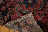 Woven reverse and tattered side of the antique Lilihan rug, featuring raspberry red and navy blue tones.