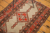 Distressed pile and tattered side of an antique Persian Malayer rug with tomato red border.
