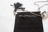 Black vegetable suede back of the handbag, showing the exterior zipper and tassel.