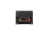 Black leather coin purse with colorful geometric rug fragment and embossed flap.