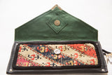 Handmade rug clutch with a green suede interior flap and a colorful geometric wool panel.
