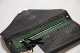 Green vegetable suede pocket with a metal zipper inside the textured black clutch.