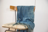 Close-up of hand woven Batik Indigo Throw featuring variegated blue dye, stitched lines, and fringed edge.