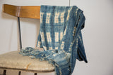 Vintage hand-woven indigo textile with faded cream batik pattern, softly draped.